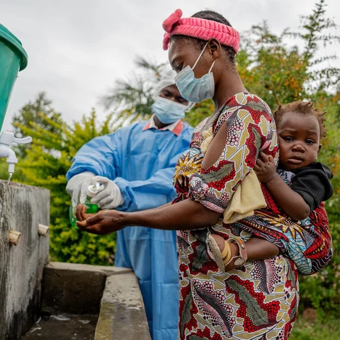 Een moeder wast haar handen in een gezondheidscentrum na het volgen van de instructies over ebola.