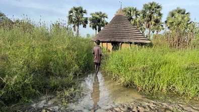 A young boy standing in front of a flooded house