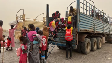 save_the_children_staff_assisting_women_and_children_board_truck