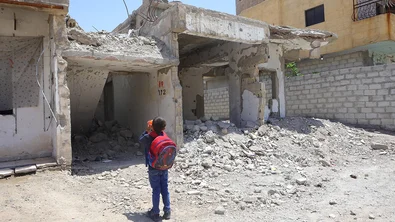 De zevenjarige Issa staat voor zijn gebombardeerde school in Raqqa, Syrië, waar hij woont