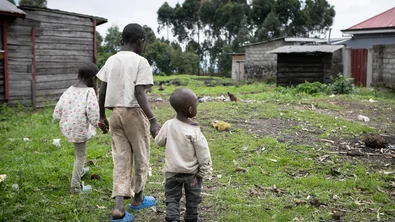 Drie broers lopen in het vluchtelingenkamp aan de rand van Goma in DRC