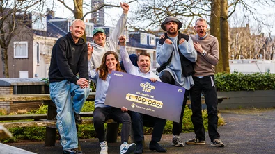 De leden van Goldband en medewerkers van Save the Children met een cheque van 100.000 euro