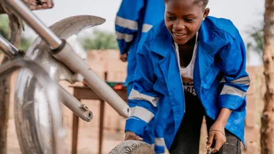 Door Save The Children getrainde monteur Bea werkt aan een motor