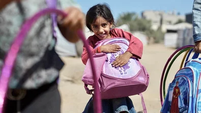 Een meisje nadat ze een schooltas en schoolkit heeft gekregen van Save the Children.