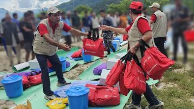 Medewerkers van Save the Children delen hygiënepakketten uit aan een gemeenschap die getroffen is door de plotselinge overstroming