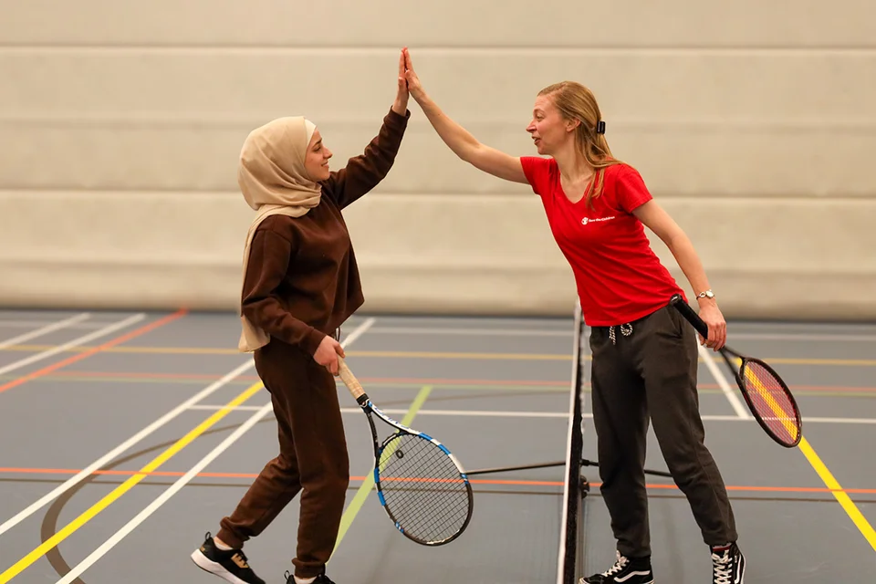 Een deelnemer van de sportcarrousel geeft een high five aan een medewerker Een deelnemer van de sportcarrousel geeft een high five aan een medewerker