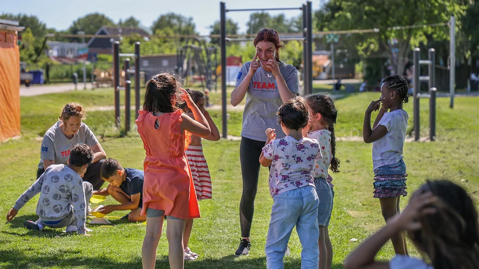 Kinderen spelen in een groep onder leiding van een TeamUp vrijwilliger
