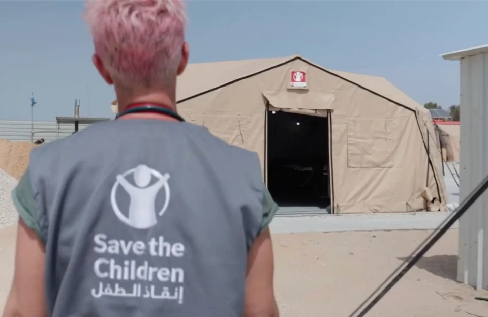 Mederwerker Save the Children loopt naar hulp-tent