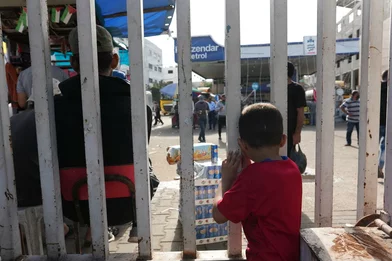 Een kind staat achter een hek in Gaza