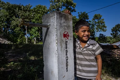 Fatra staat bij een kraan, aangelegd door Save the Children in Indonesië