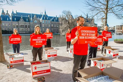 Medewerkers van Save the Children staan met borden voor de hofvijver in Den Haag Medewerkers van Save the Children staan met borden voor de hofvijver in Den Haag