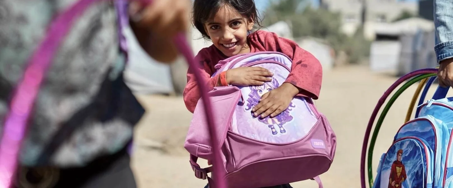 Een meisje nadat ze een schooltas en schoolkit heeft gekregen van Save the Children.