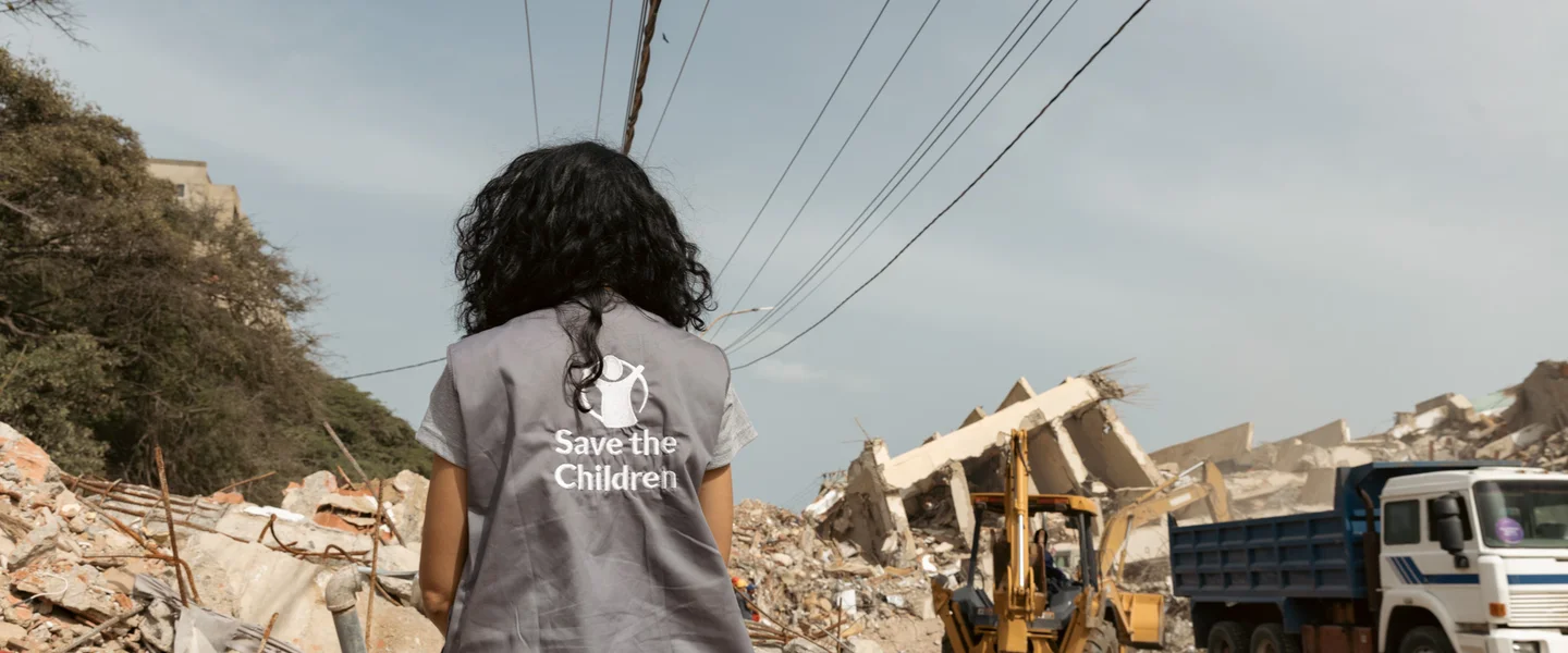 Save the Children hulpverlener staat bij een plek die getroffen is door een aardbeving