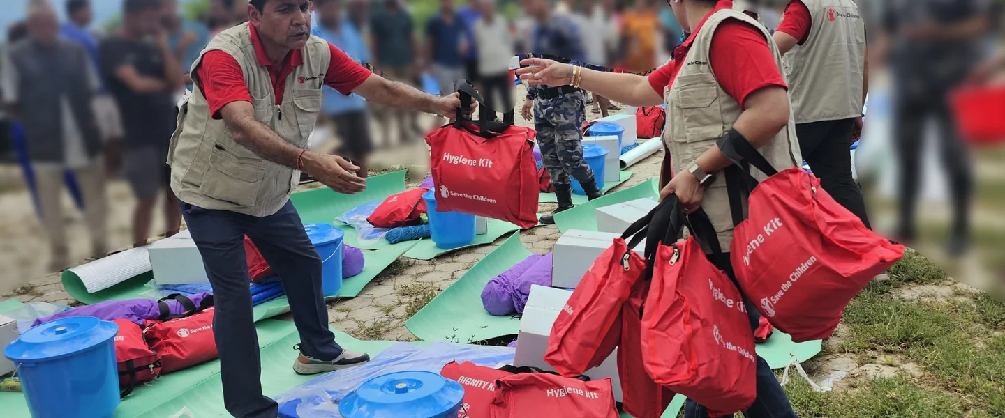 Medewerkers van Save the Children delen hygiënepakketten uit aan een gemeenschap die getroffen is door de plotselinge overstroming