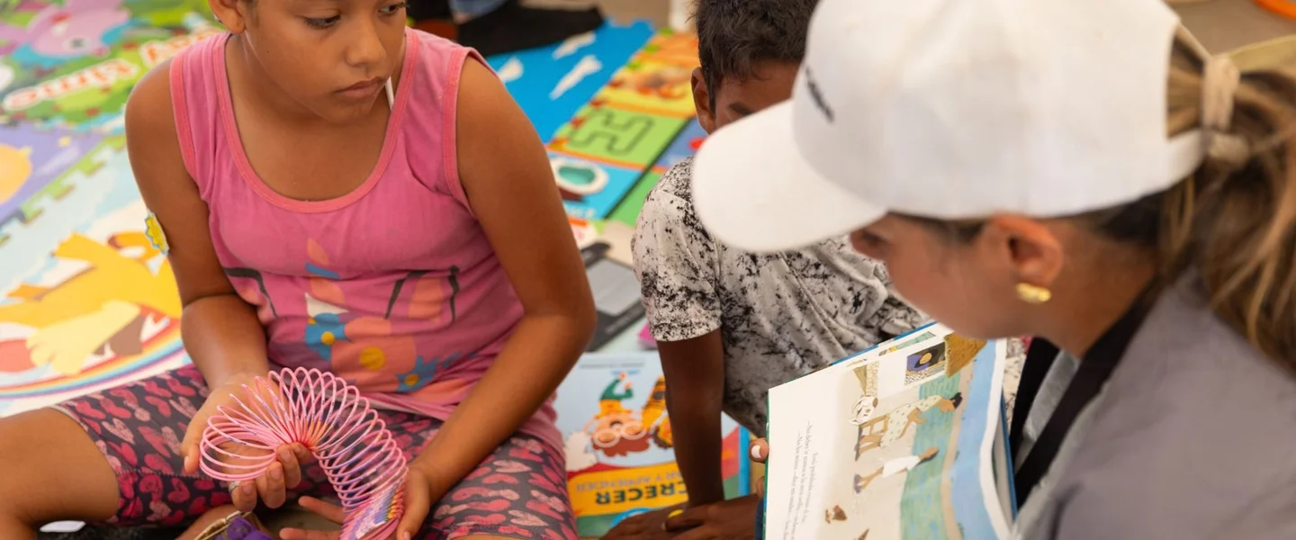 Save the Children medewerker leest een verhaal voor aan Emma en andere kinderen*