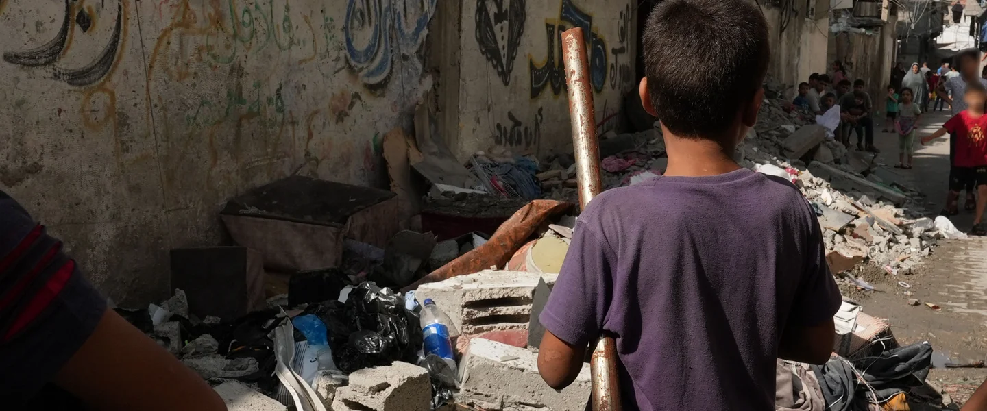 Een kind dat tussen een hoop puin op een straat in Gaza staat