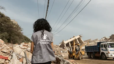 Save the Children hulpverlener staat bij een plek die getroffen is door een aardbeving