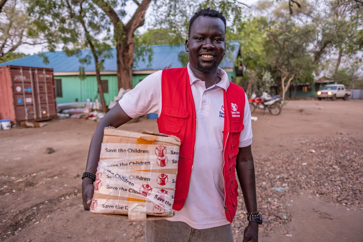 coördinator met doos hulpmiddelen van Save the Children